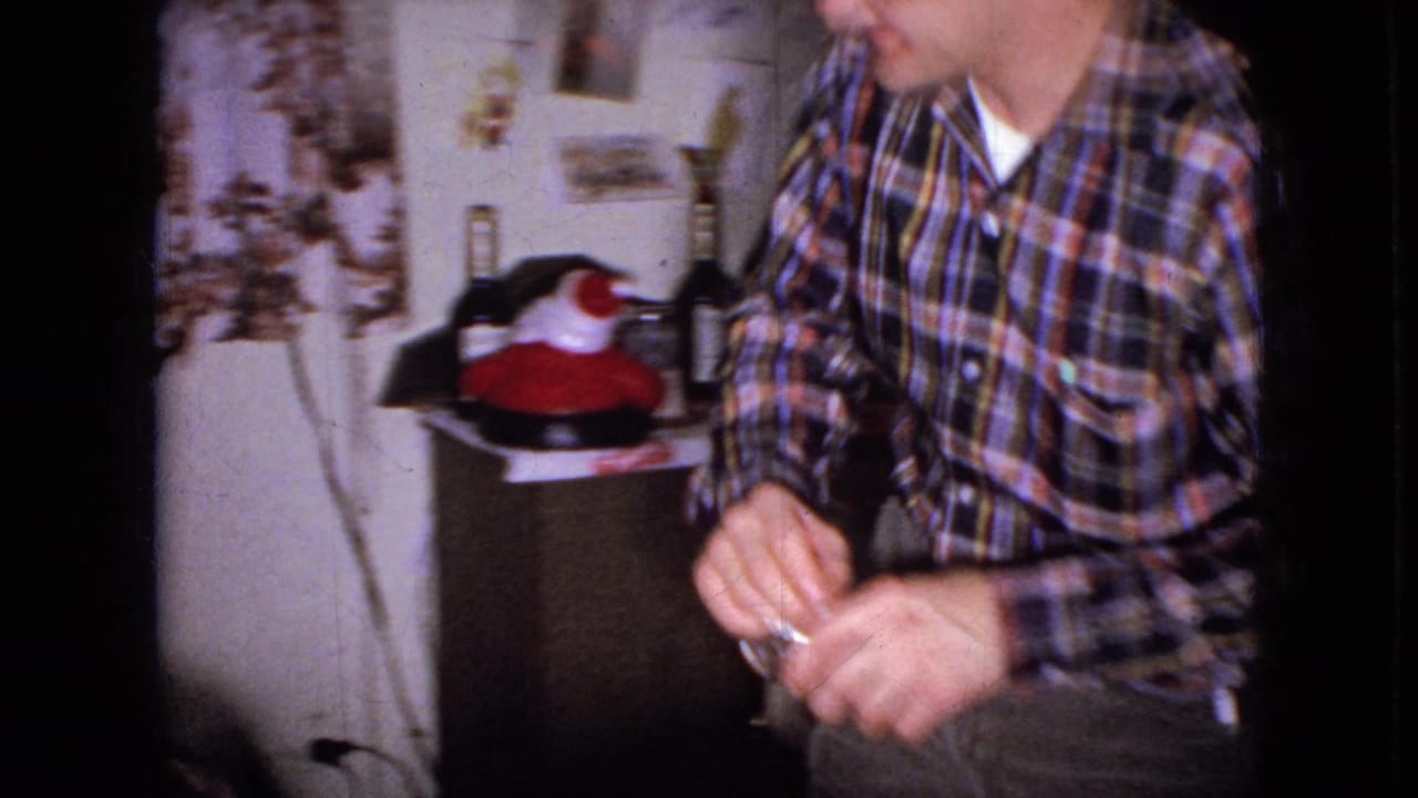 Man in a plaid shirt partly framed near a side cabinet in the living room.