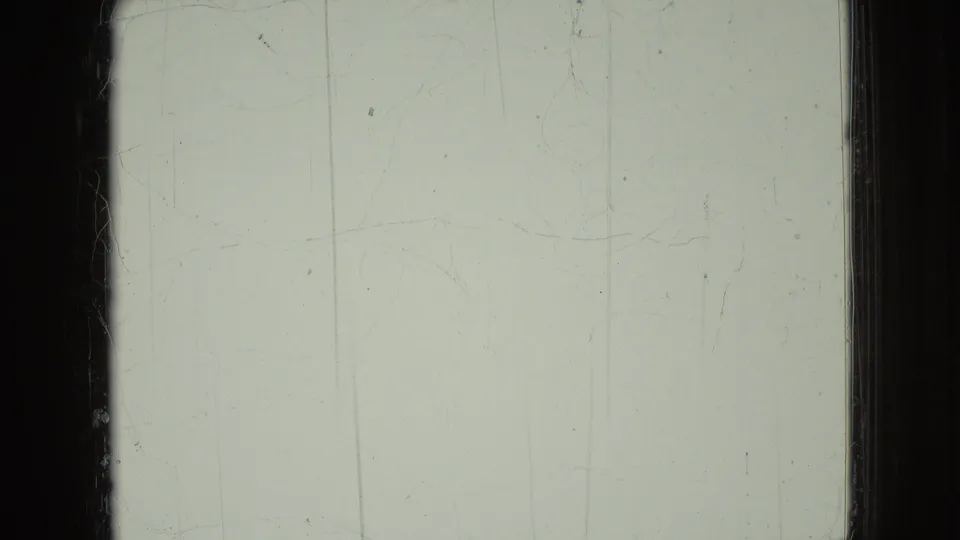 A pale, overexposed 8mm frame with visible scratches, dust, and dark frame borders, likely from the same Wellsburg, Iowa home-movie reel.
