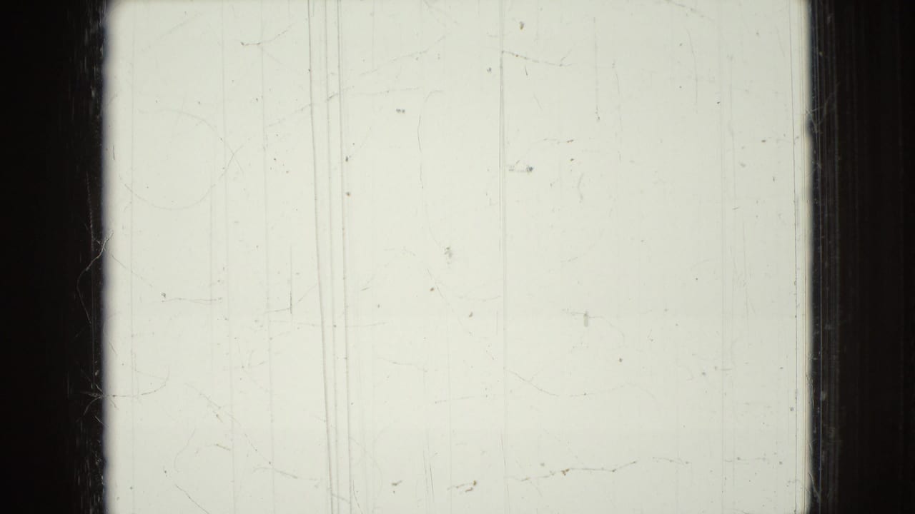 Mostly blank pale film frame with scratches and dark film borders.