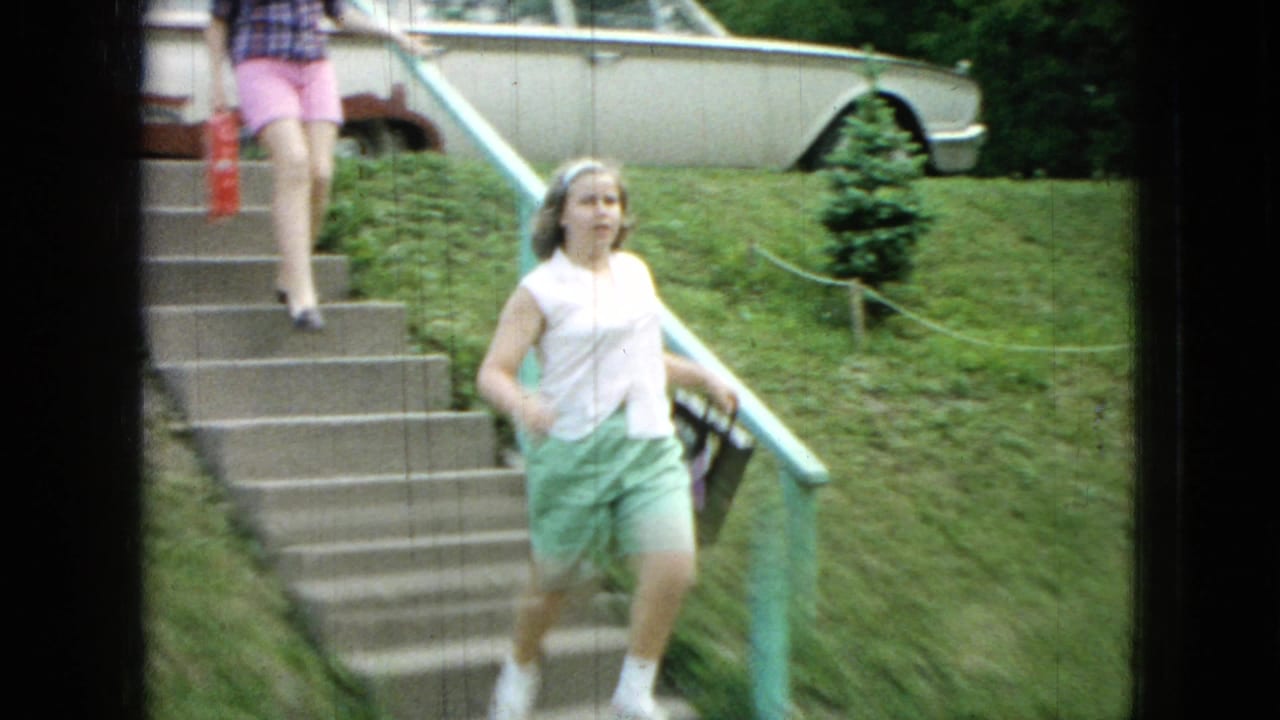 Girl in green shorts walks down concrete steps in a grassy yard.