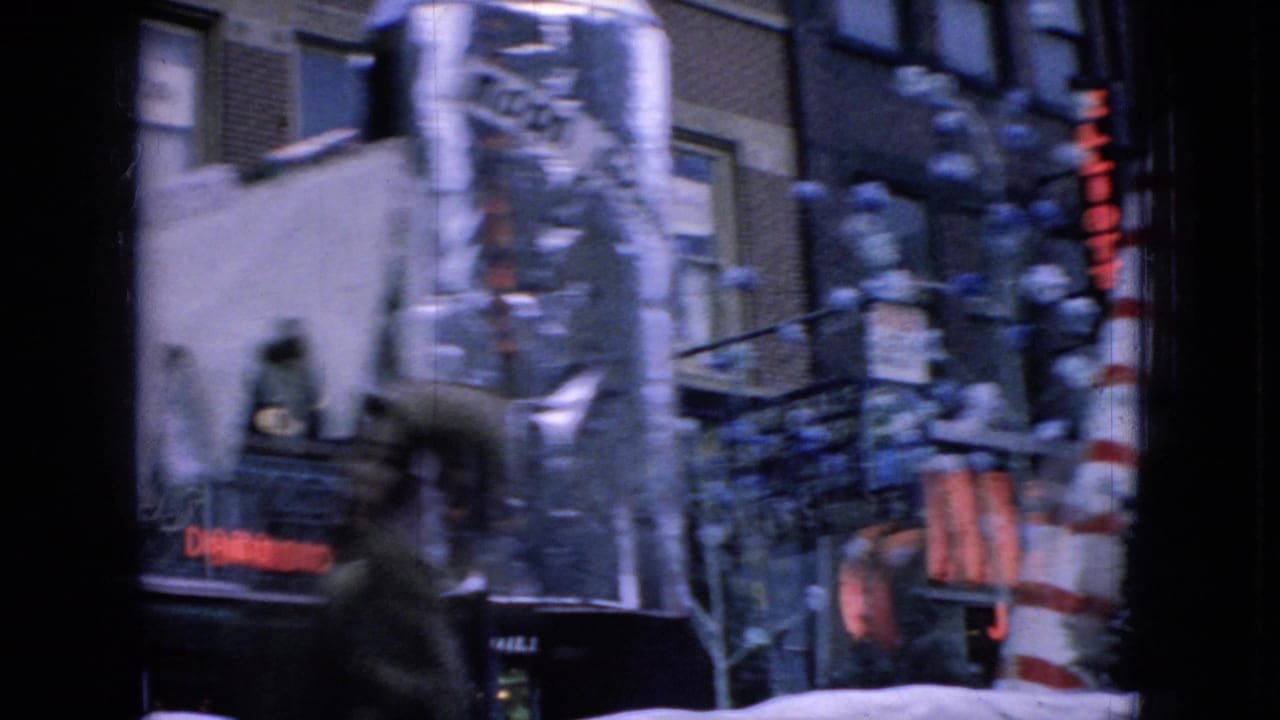 Holiday float details with a large candy cane, snowy facade, and downtown building fronts.