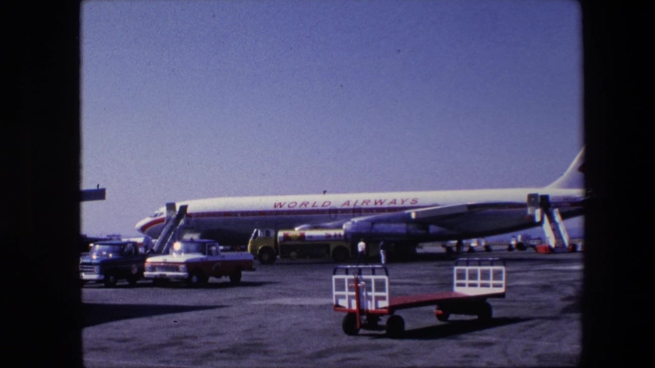 Parked World Airways aircraft with service vehicles and stair trucks on the tarmac.