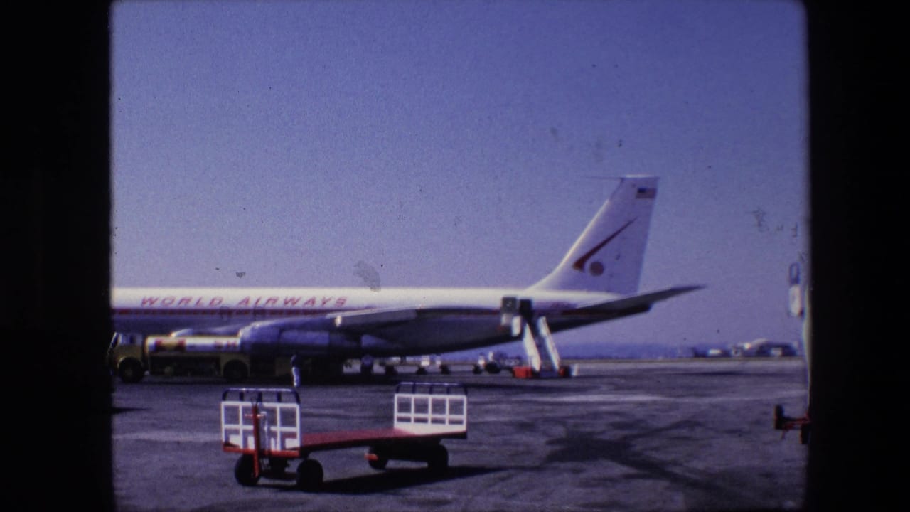 Side view of a World Airways jet on the tarmac in 1967 archival 8mm footage, with ground service equipment and runway pavement in view.
