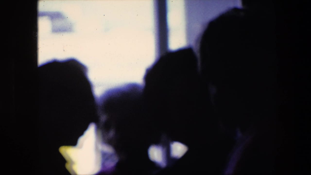 Silhouetted travelers stand in an Amsterdam airport terminal in 1967, with a red-and-white commercial airplane visible through the bright window beyond them.