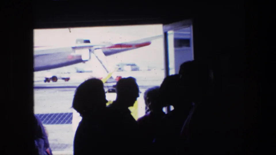 Dark figures gather near the airport window as the airplane remains visible outside, creating a high-contrast 1967 Amsterdam travel scene.