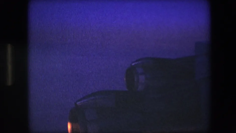 The passenger-window view shows a dark engine or wing silhouette in the foreground with distant snow-covered ridges under a fading blue-purple sky.