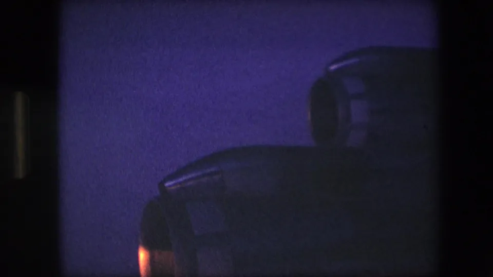 Close nighttime view of overlapping aircraft engine housings, with blue color cast, soft focus, and a small orange glow near the lower left edge.