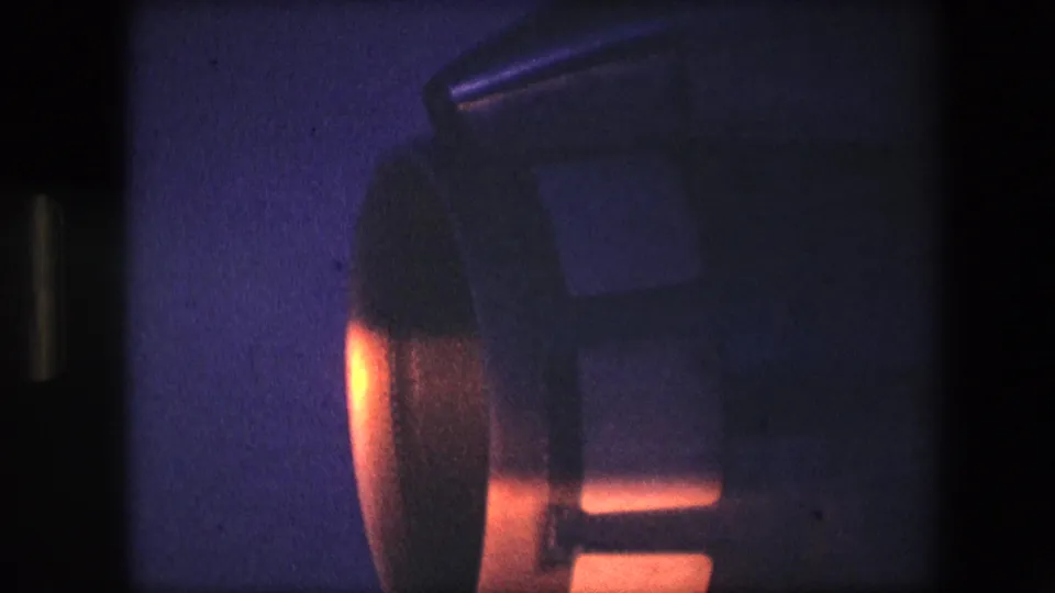 Close 8mm view of an aircraft engine housing at night, showing a bright orange glow beneath dark rounded metal forms and blue grainy exposure.