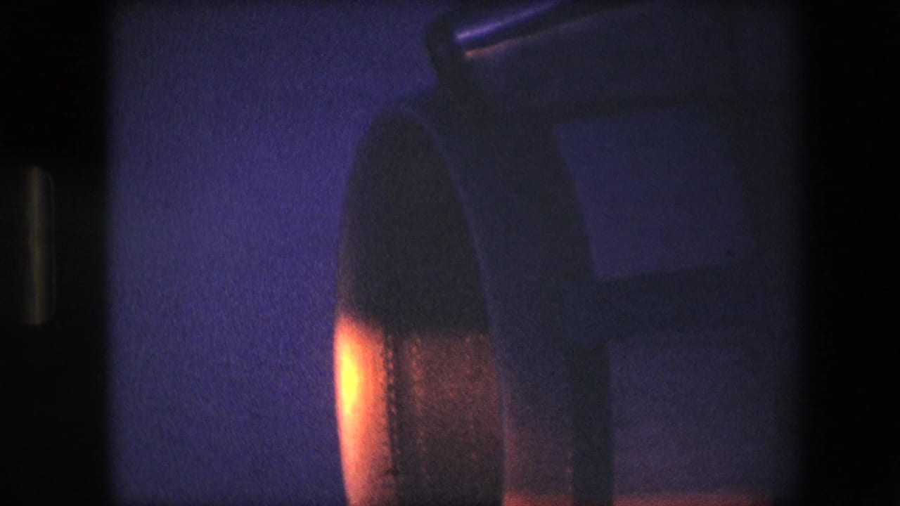 Turbine-like rounded machinery partly visible beside a dark vertical film border.