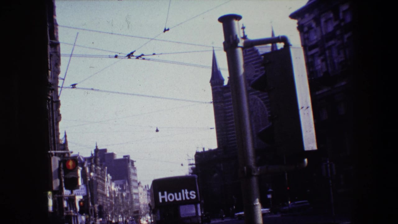 Angled street view with tram wires, Hoults truck, traffic signal, tall buildings, and spire.