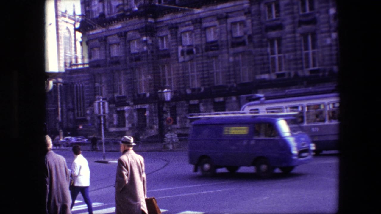 Amsterdam, 1967 street scene with pedestrians in coats near a zebra crossing while a blue van, tram, and historic buildings appear in the background.