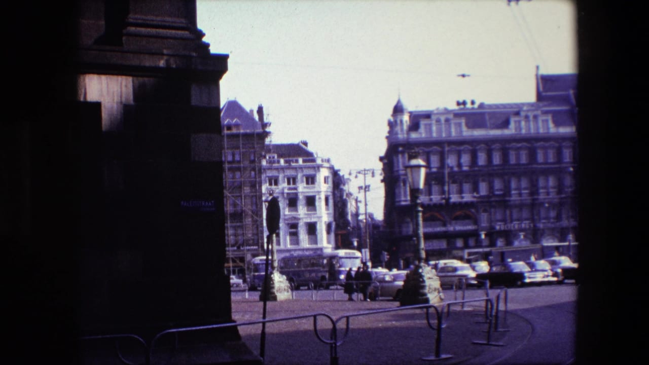 Amsterdam town-square street scene in 1967 seen from shadow, with vintage cars, pedestrians, tram wires, street lamps, and ornate multi-story buildings beyond.
