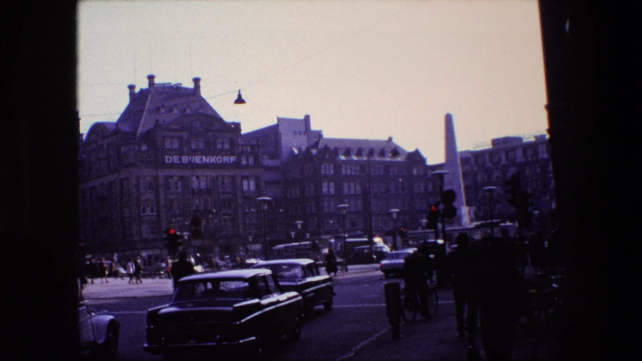 City intersection with cars, cyclists, pedestrians, traffic signals, and department store frontage.