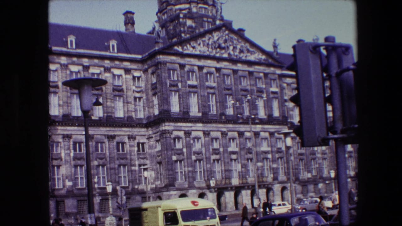 1967 Amsterdam frame of the Royal Palace on Dam Square, with the ornate stone building above pedestrians, older cars, street lamps, and a yellow van at street level.