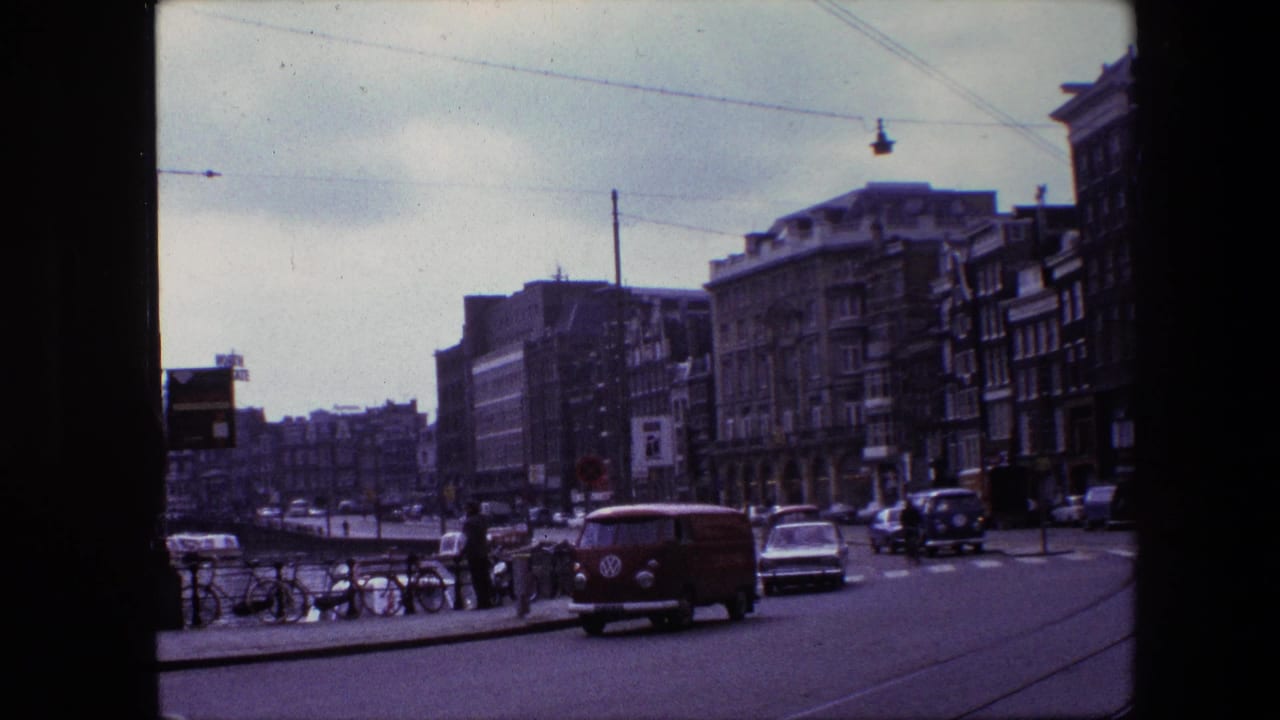 Urban canal-side street with cars, bicycles, pedestrians, and a red van.