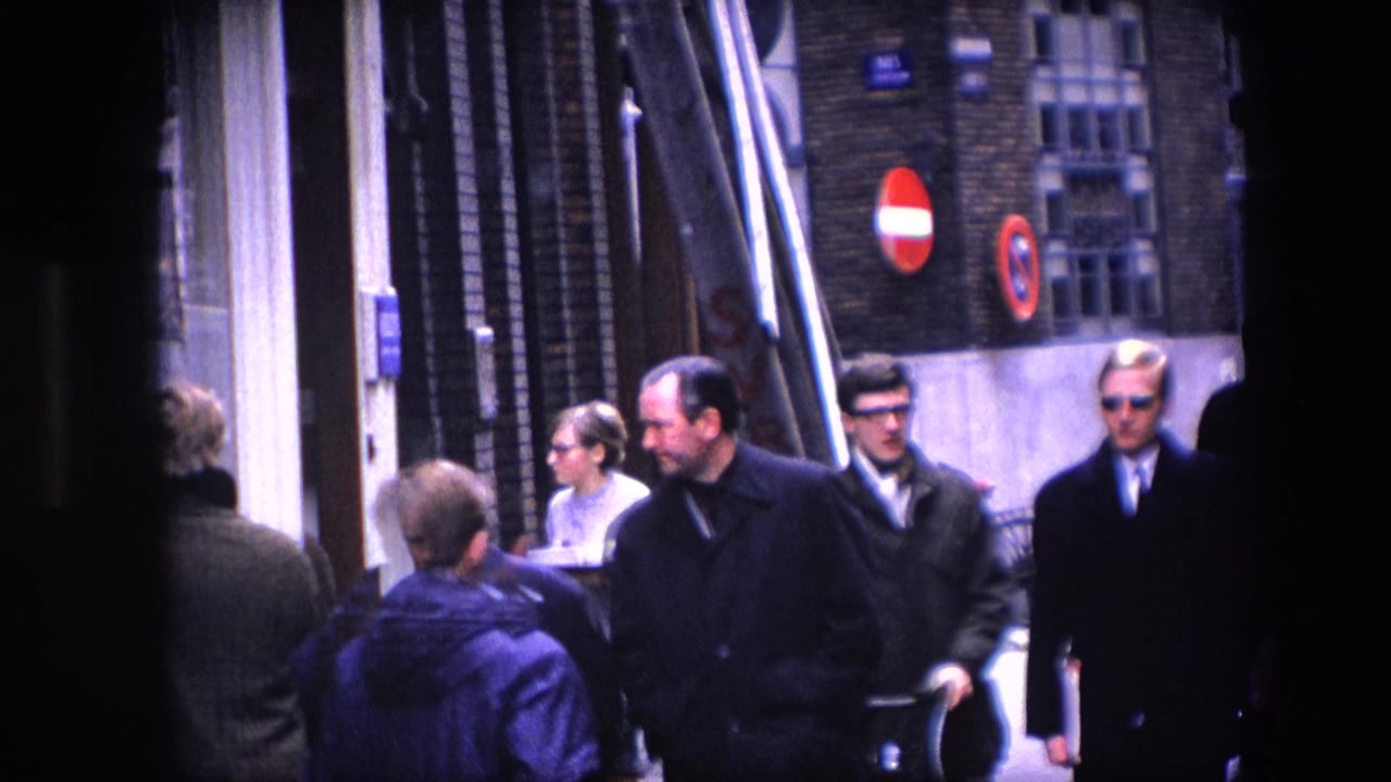 The wider street view shows men in coats, passersby, shopfronts, and circular traffic signs in a 1960s city scene identified by metadata as Amsterdam.