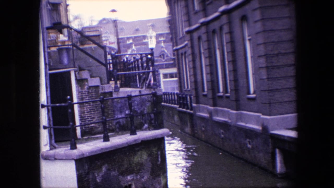 Amsterdam canal scene from supplied 1967 metadata, showing high water between masonry buildings, a small railing, steps, and distant rooftops.