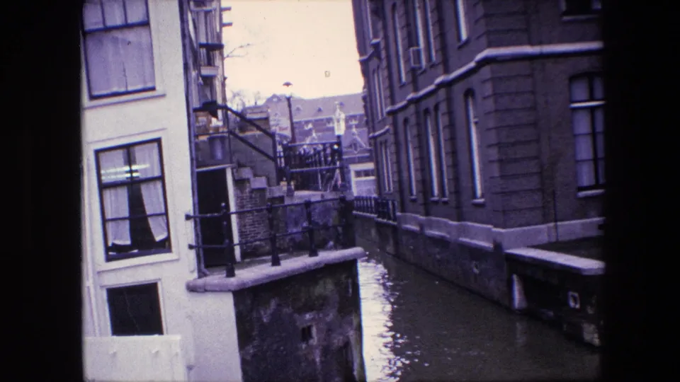 Amsterdam canal view from supplied 1967 metadata, with tall windows, black railings, exterior steps, and high water along the building edge.