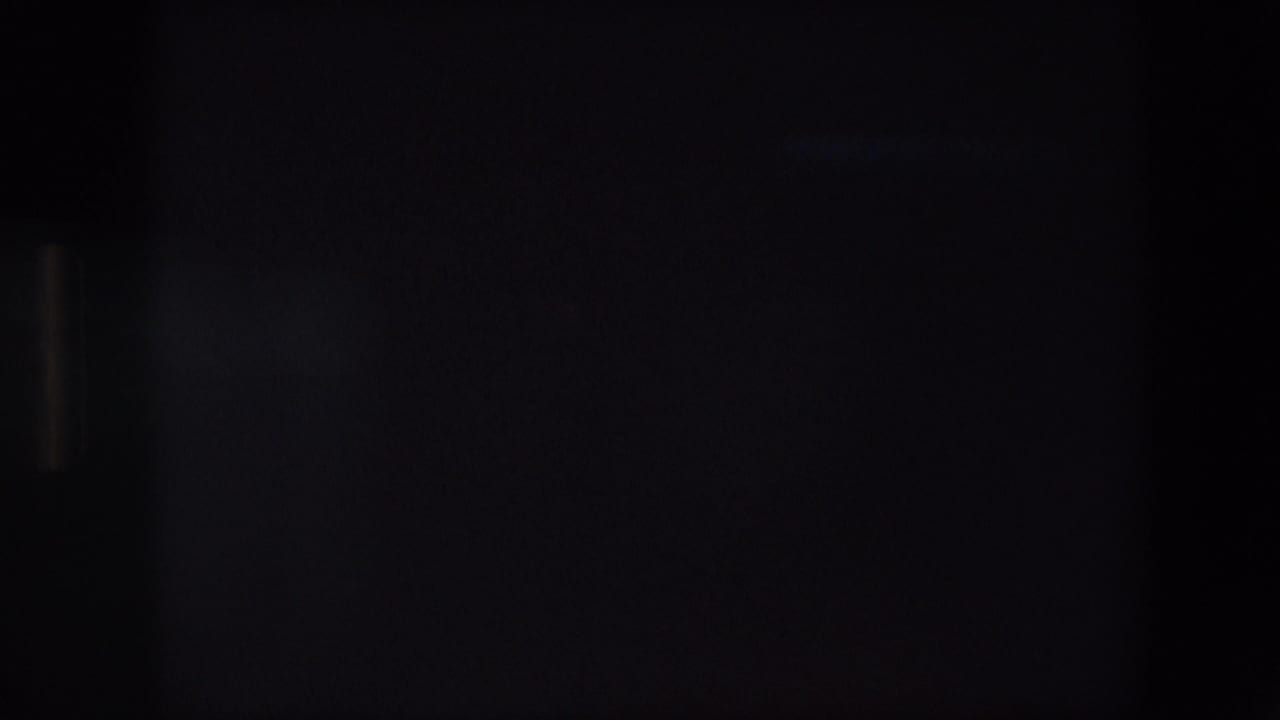 Very dark 8mm frame, likely an exposure or transition moment within the home-movie clip.