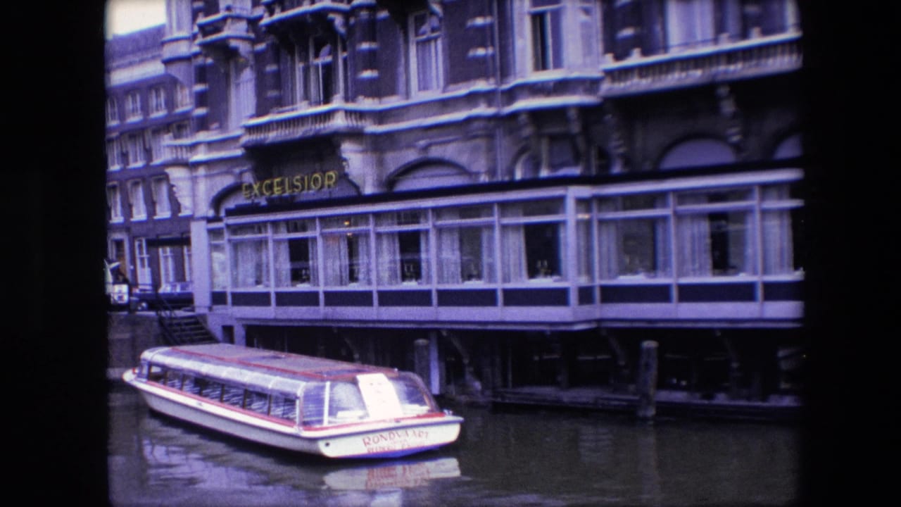 Final frame of the 1967 Amsterdam canal scene, with the white rondvaart boat at the bottom of the frame and the Excelsior hotel frontage filling the background.