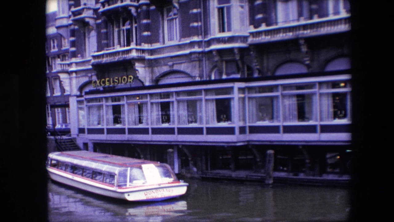 1967 Amsterdam canal view showing a small boat marked Rondolet beside the Excelsior restaurant and its glass-enclosed waterfront dining area.