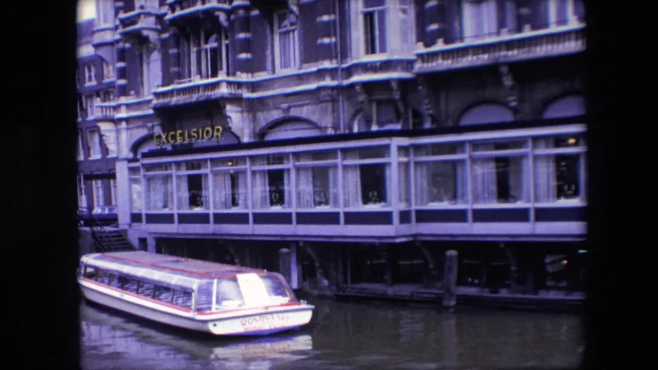 1967 Amsterdam canal view showing a small boat marked Rondolet beside the Excelsior restaurant and its glass-enclosed waterfront dining area.