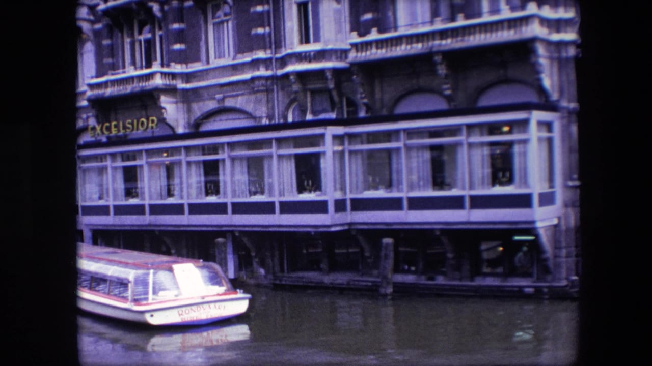 Amsterdam waterfront restaurant facade with the Excelsior sign and a moored canal boat partly framed at the lower left.