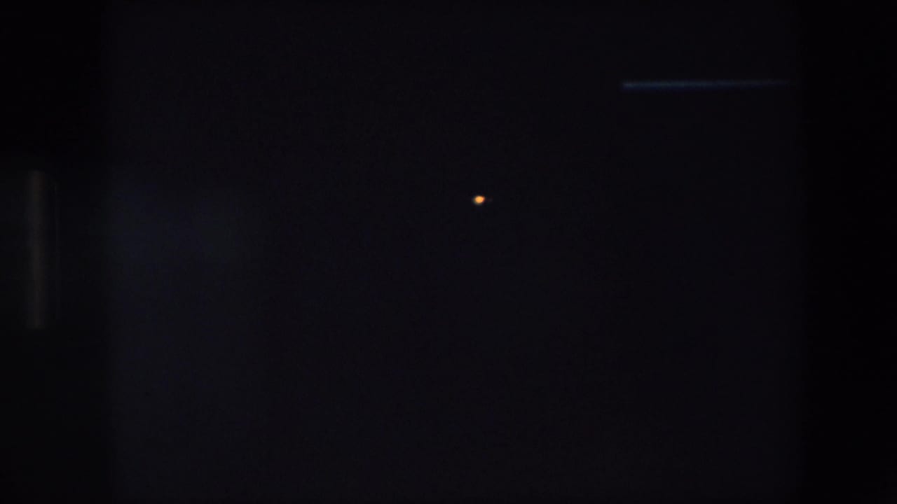 The opening 8mm frame is largely obscured by a dark foreground area, with only a small point of light and faint structural edges visible.