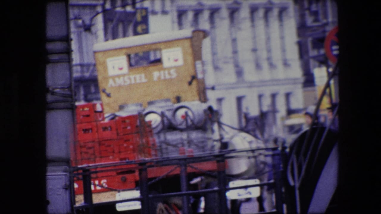 A clearer 1967 Amsterdam frame shows a white horse pulling a wooden Amstel Pils delivery cart with red crates and metal kegs along a street lined with older buildings.