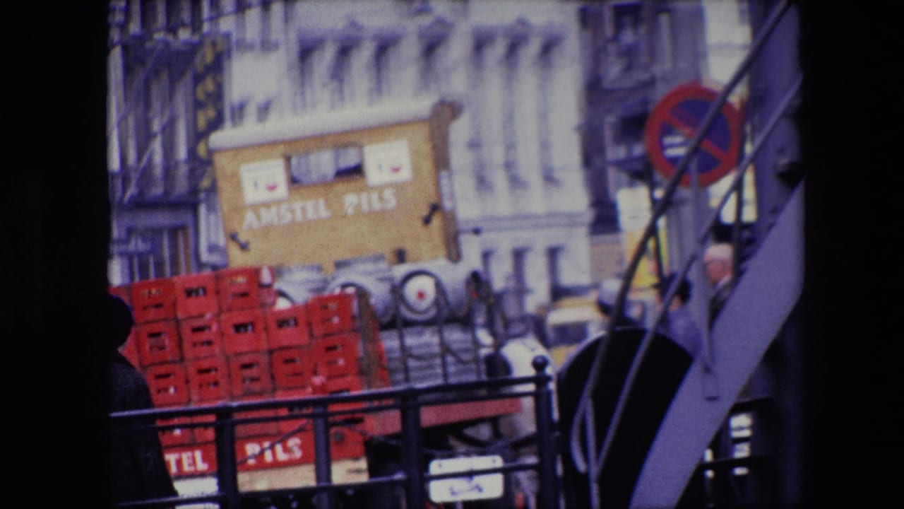 1967 Amsterdam street view with red Amstel Pils crates, a delivery vehicle area, pedestrians partly visible, and building facades behind a railing.