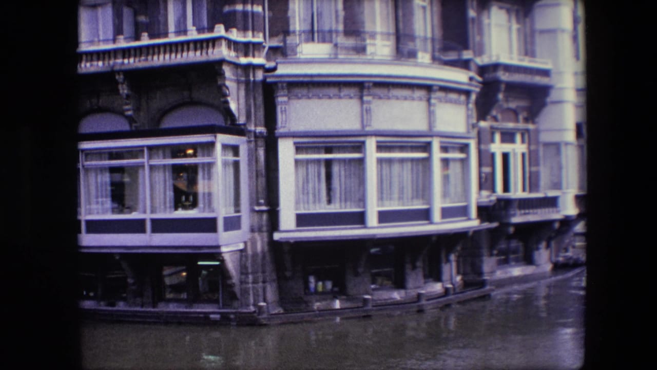 Waterside facade with enclosed window bays, curtains, balconies, and canal water.