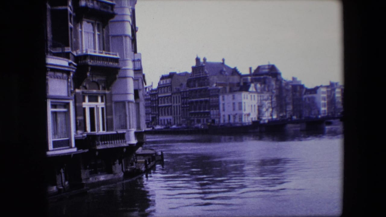 Amsterdam canal frontage in 1967, showing older multi-story buildings, a close facade at left, and calm water in the foreground.