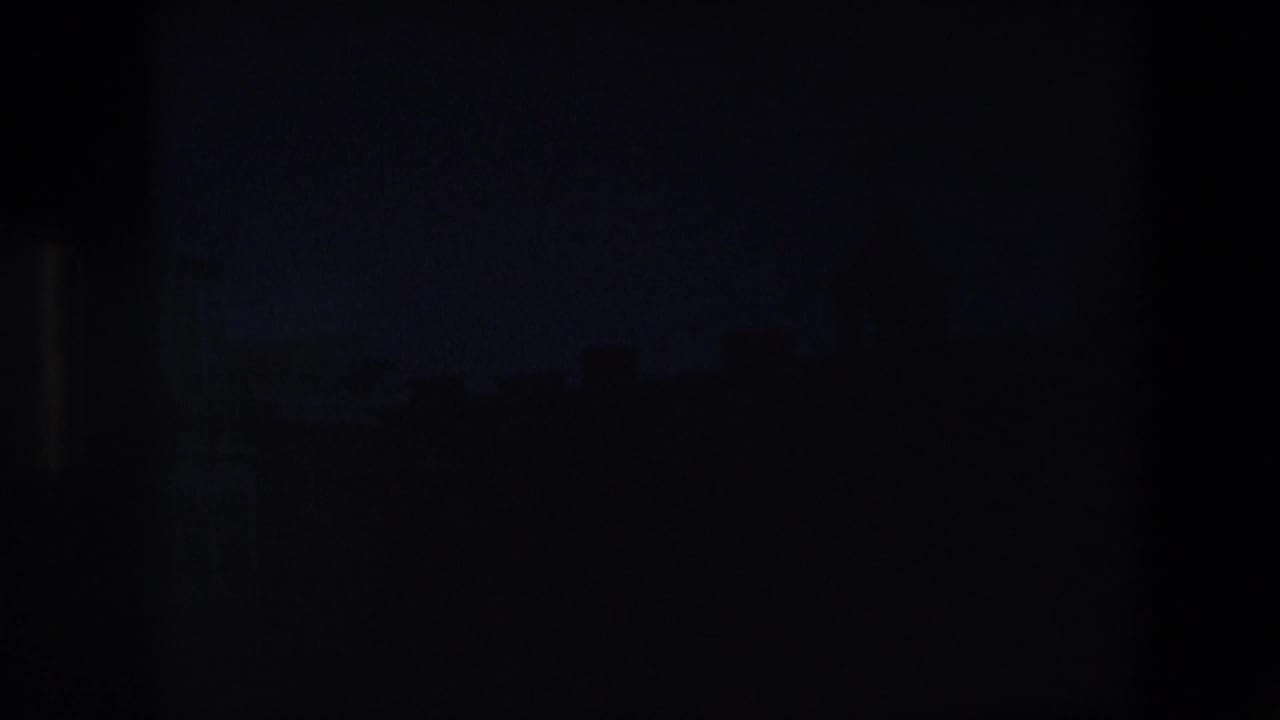 Underexposed 1967 Amsterdam home-movie frame with faint roof and tower detail at the top and a large dark lower area inside the film gate.