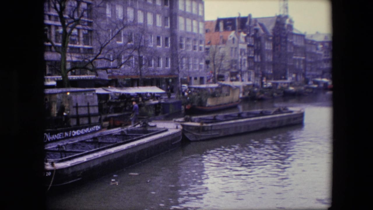 Canal boats and houseboats moored beside older urban buildings.