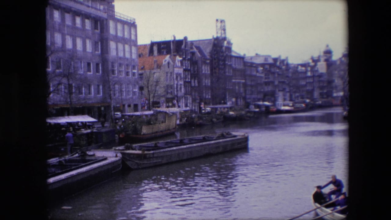 Canal lined with tall buildings, moored boats, and a rowboat entering the lower right.