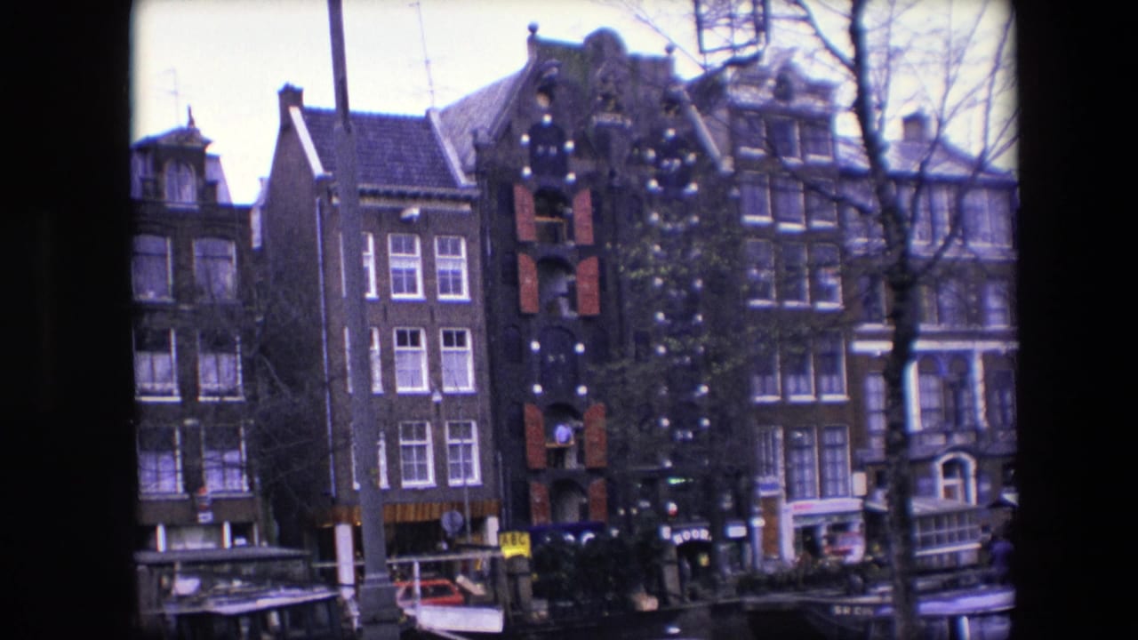 Narrow canal houses beside water with a decorated building, bare trees, boats, and small street details.
