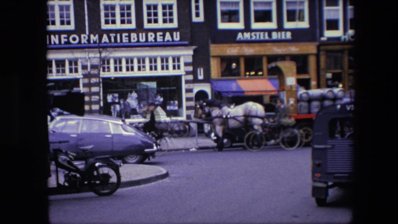 Amsterdam street scene from the supplied 1967 home-movie metadata, showing a horse-drawn cart near classic cars, bicycles, a motorcycle, pedestrians, and storefront signage.
