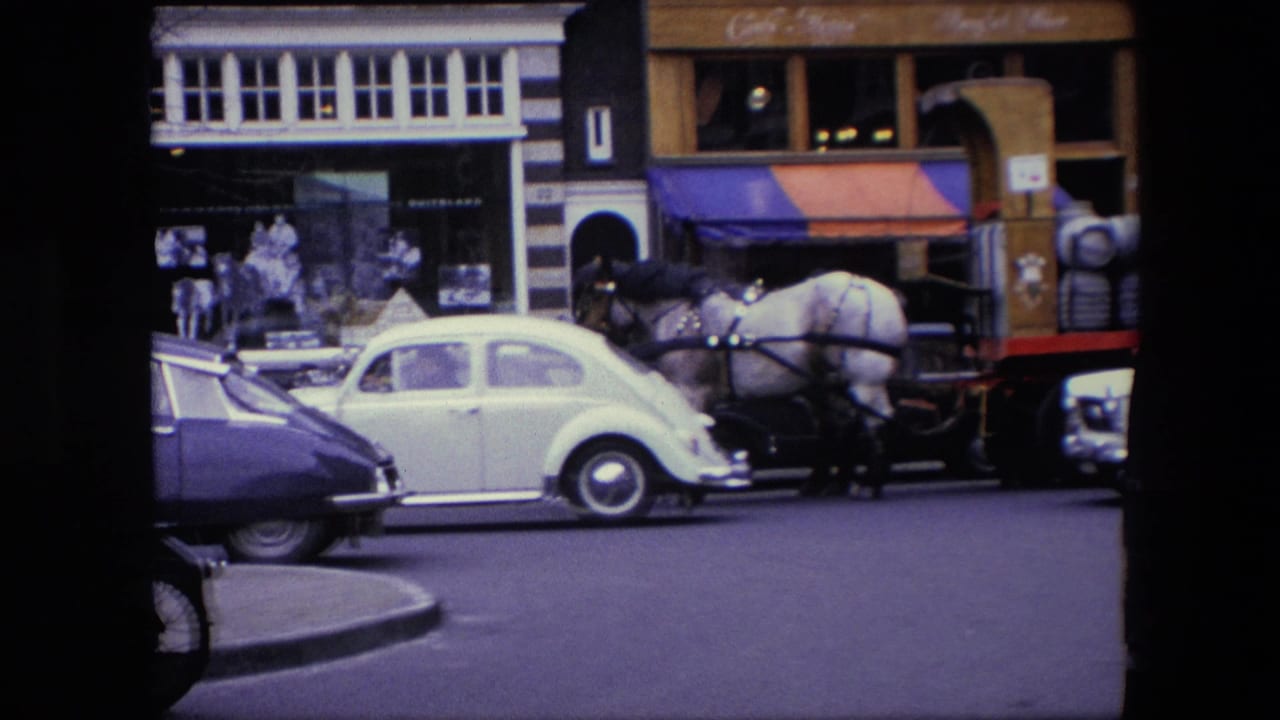 The 1967 Amsterdam street view shows a white Volkswagen Beetle passing close to a horse-drawn cart, with bicycles, pedestrians, and commercial storefronts behind them.