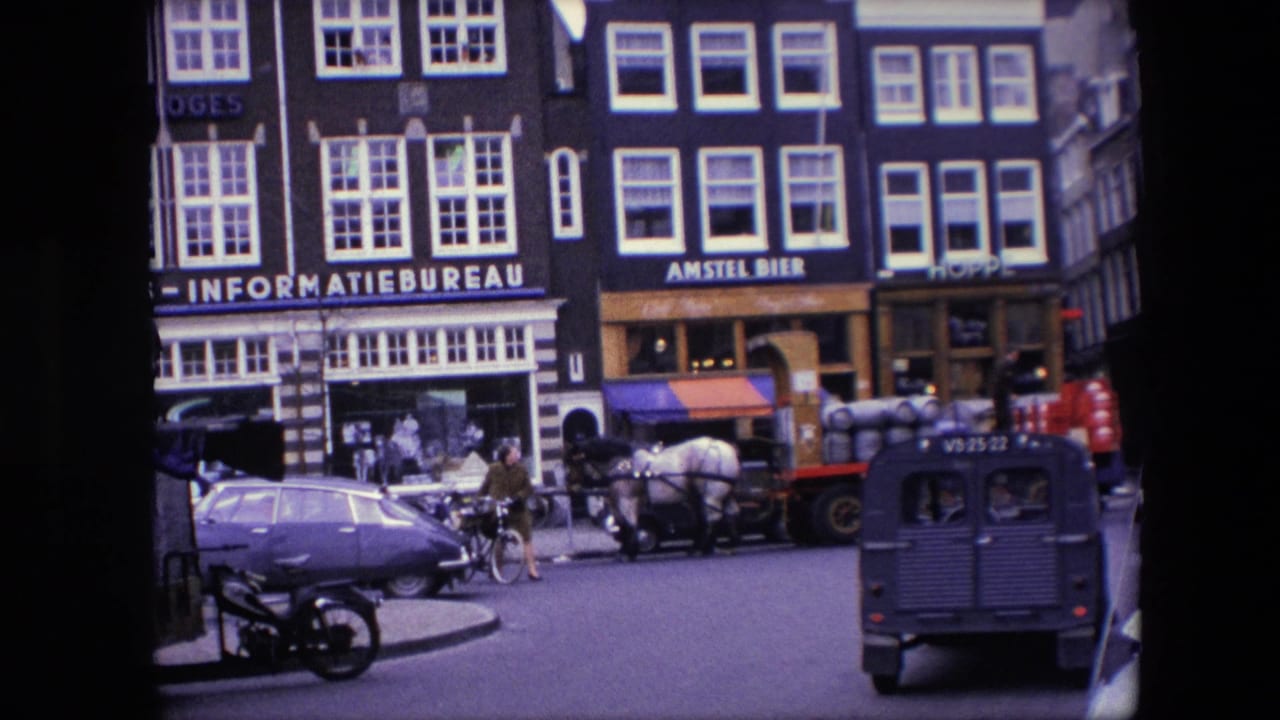 Late frame of 1967 Amsterdam street activity with classic cars, a cyclist, pedestrians, a horse-drawn cart, a dark van, and prominent INFORMATIEBUREAU and AMSTEL BIER signs.