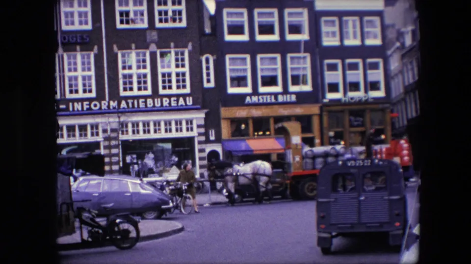 Late frame of 1967 Amsterdam street activity with classic cars, a cyclist, pedestrians, a horse-drawn cart, a dark van, and prominent INFORMATIEBUREAU and AMSTEL BIER signs.