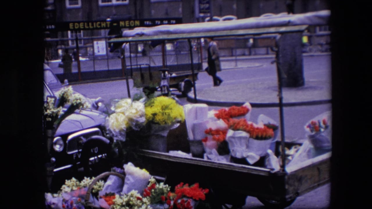 Flower cart in the foreground with a pedestrian crossing the street behind it.