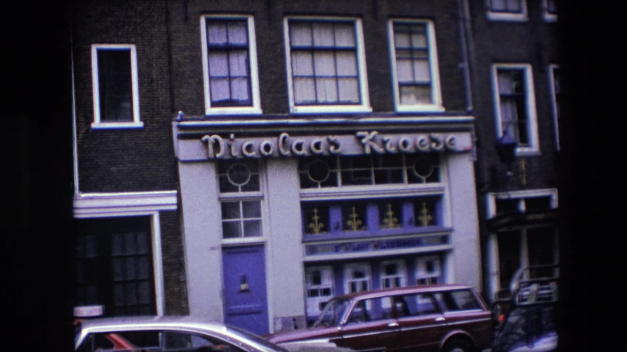 1967 Amsterdam 8mm frame showing the Nicolaas Kroese facade with a purple entrance, white window trim, dark brick upper floors, and cars parked at the curb.