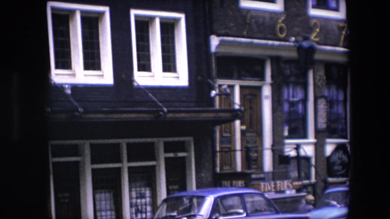 Closer 1967 Amsterdam street detail, with white-trimmed windows, a doorway below address numerals, shopfront glass, and a blue car parked at the curb.
