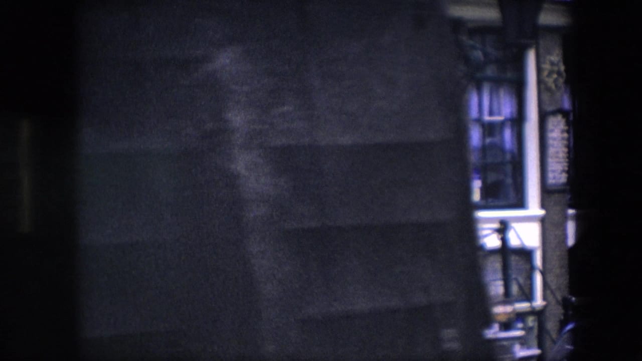1967 8mm frame identified as Amsterdam, showing a dark building facade with windows, white trim, doorway details, and a partially visible Five Flies sign.