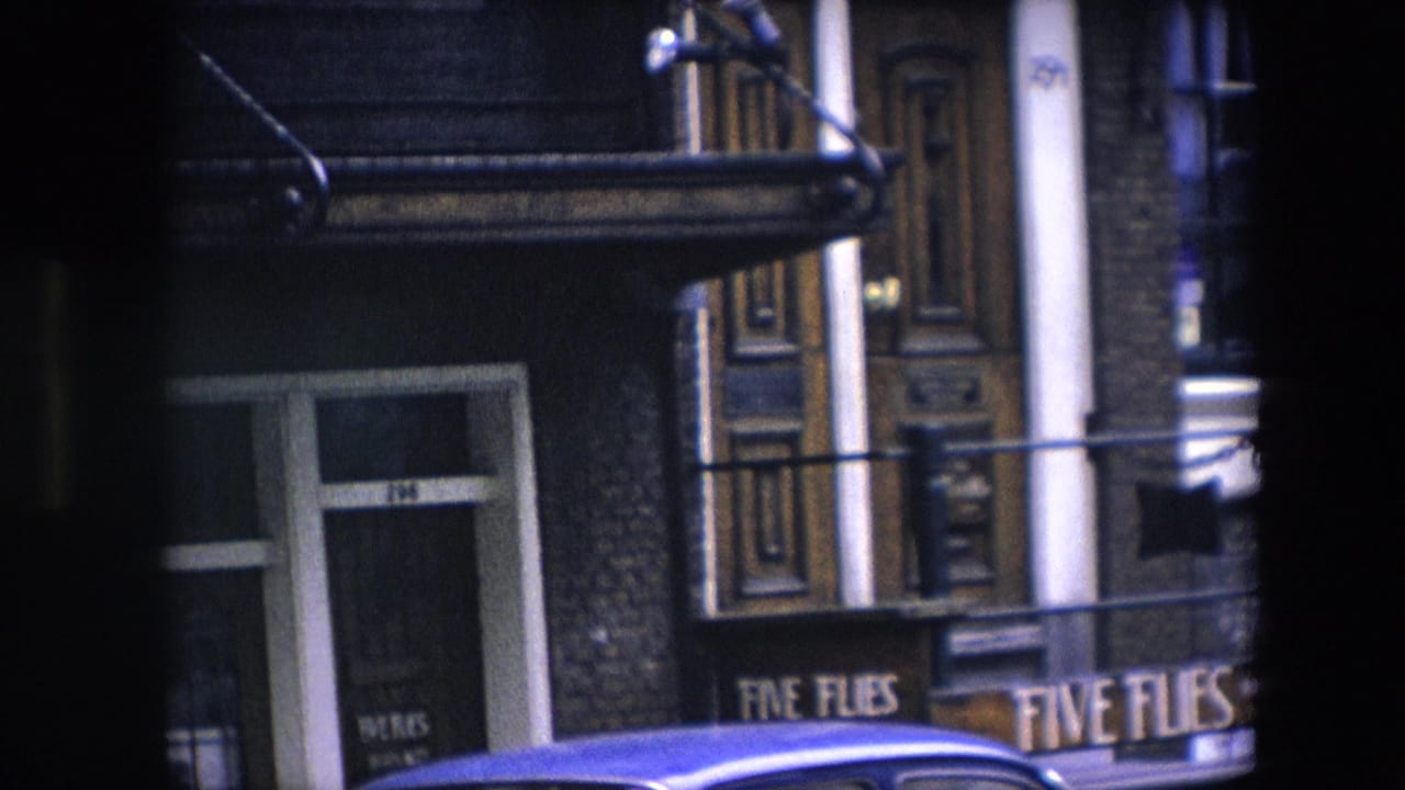 1967 8mm frame identified as Amsterdam, showing the Five Flies sign beside an ornate wooden doorway with a blue car roof crossing the lower frame.