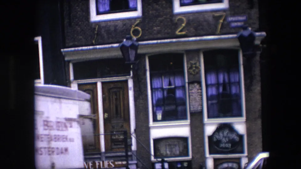 1967 Amsterdam lower-building view with a wooden doorway, white-trimmed windows, purple curtains, Five Flies signage, 1627 numerals above, and a partial van at the left edge.