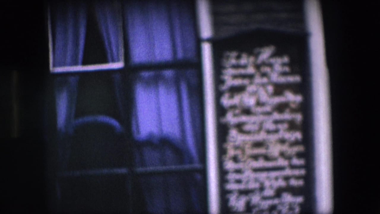 Closer view of a plaque between windows on a dark building facade.