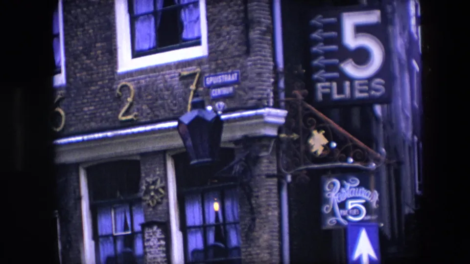 1967 Amsterdam frame showing the Spuistraat street sign, 5 Flies restaurant signage, a blue one-way arrow, address numerals, and curtained windows on a brick townhouse facade.