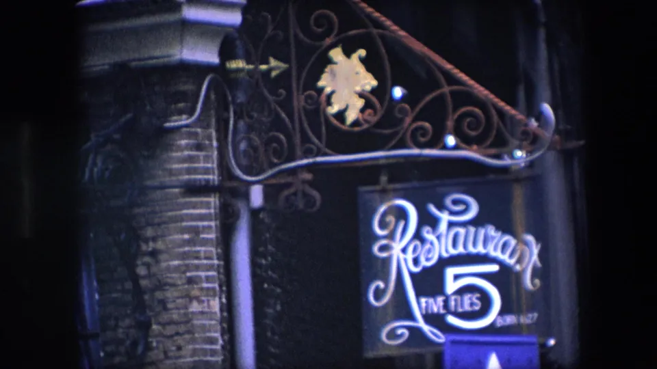 Closer 1967 Amsterdam night view of the Restaurant Five Flies sign, with ornate wrought iron above it and dark brickwork behind.