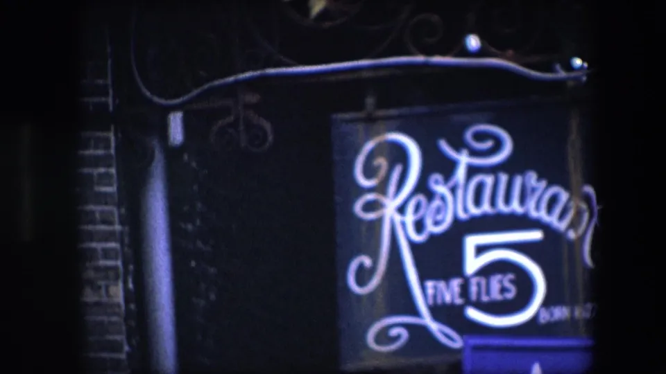 Tight 1967 Amsterdam frame of the Restaurant Five Flies sign, showing bright script lettering, the large number 5, and soft 8mm night bloom.